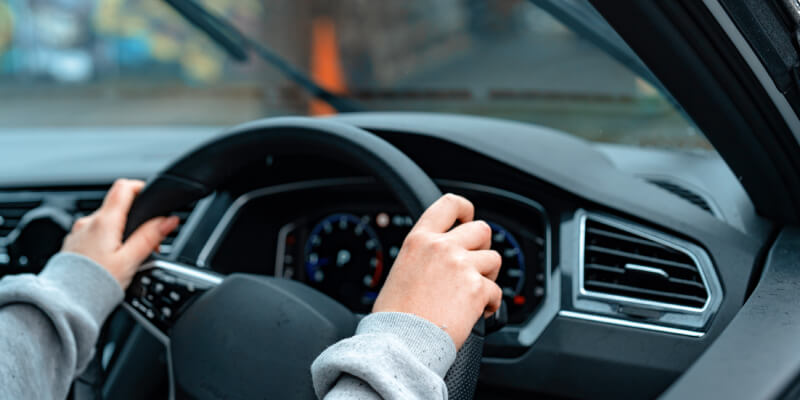 Hands gripping steering wheel in car