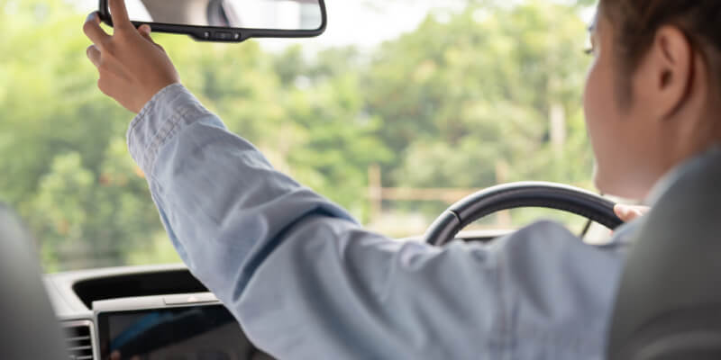 Girl reaching to adjust rearview mirror