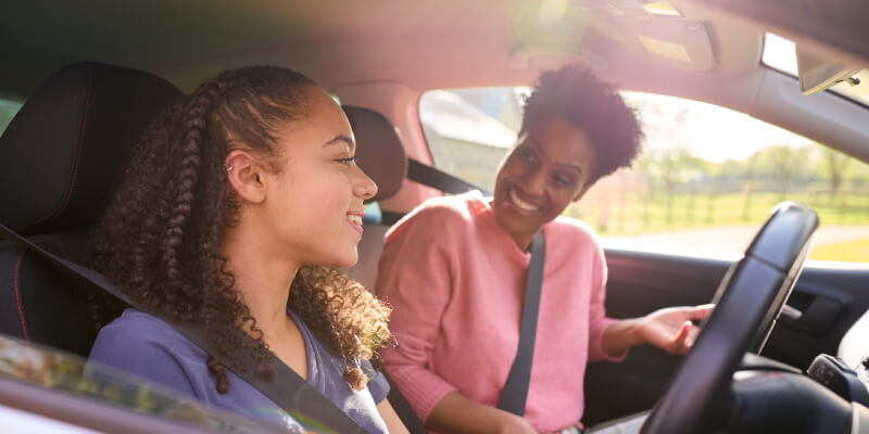 Girl and woman in car smiling at each other