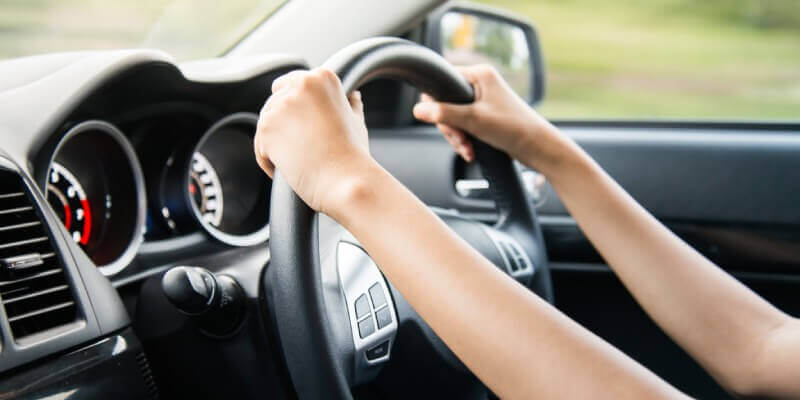 Hands gripping steering wheel in the car