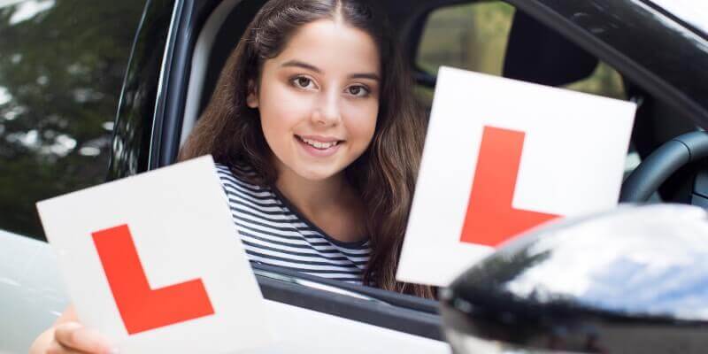 Girl in a car holding up l-plates