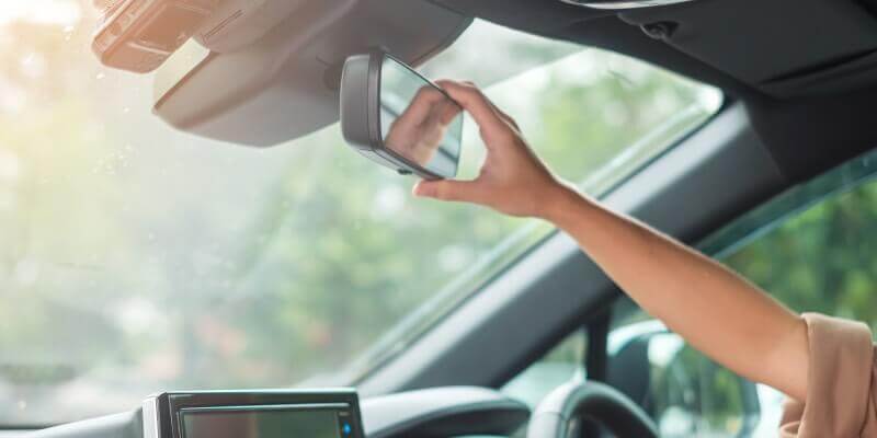 Hand reaching to adjust rearview mirror in the car